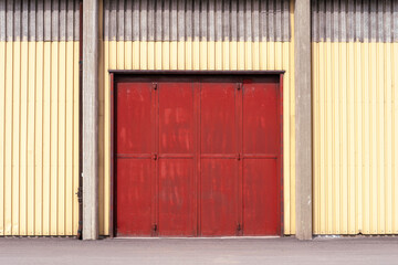 a red metal gate on a yellow metal wall