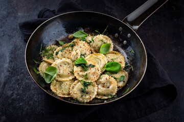 Traditional Italian medaglioni pasta staffed with parmesan cheese and pesto served as close-up in a rustic frying pan with copy space