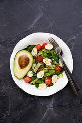 Fresh healthy vegetable salat:avocado, cucumber, tomatoes, spinach, couscous, quail eggs, flax seeds on marble background. Top view.