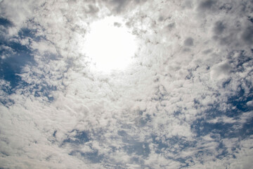 The sky is cloudy and the sun is shining through the clouds. The sun is creating a bright spot in...