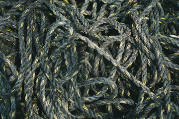 Pile of old black and yellow frayed boat rope background, pattern of twisted ropes, sailing equipment, nautical background. Close up.