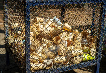 Eco-friendly disposable brown paper cups and plastic glasses used from coffee cafe, restaurants, takeaways in bin cage. Disposal garbage waste recycle.