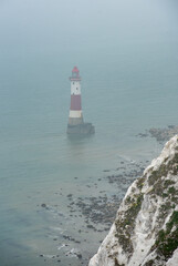 Beachy head lighthouse at the edge of white chalk cliff. Safety warning in the ocean