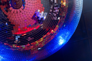 Detail of a Classic large disco ball made of small mirrors reflecting bright and warm lights on the...