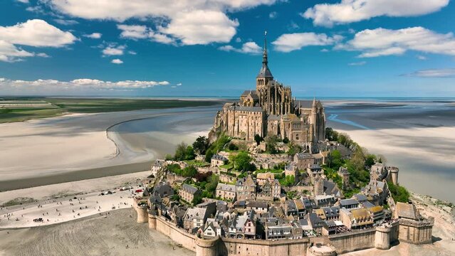 Aerial view of the famous French landmark Abbaye du Mont-Saint-Michel at brighter day with beautiful white clouds. Normandie. France.