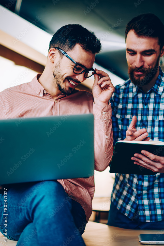Poster cheerful young employees laughing on information from textbook working in friendly atmosphere togeth