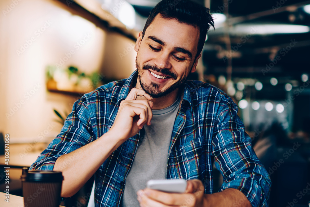 Aufkleber smiling hipster guy reading new message in social networks confirming new friend on smartphone, posi