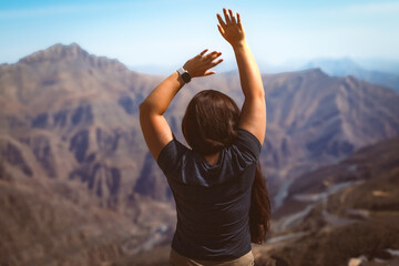 Portrait of a happy woman hiker standing on the slope of mountain ridge against mountains, blue...