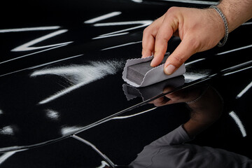 An auto service worker applying a nanocoating to a car part. Ceramic coating of a car.
