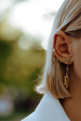 portrait of a girl
Girl's ear with three ear cartilage piercings and one lobe piercing with...