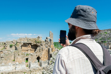 A male tourist enjoys a walk through the amphitheater among the ruins of the ancient city of Perge,...