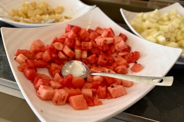 A bowl of fresh cucumber slices a versatile and healthy ingredient A fruit plate consisting of juicy red watermelon, melon, pineapple, all diced and lying in a beautiful bowl for buffet meals in a