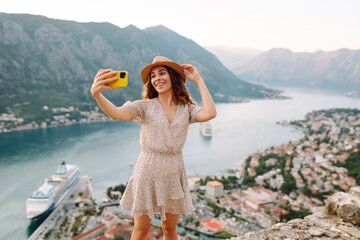 Happy tourist  with a mobile phone, takes a selfie, communicates via video link  against the backdrop of attractions. Lifestyle, travel, rest, weekend, active life.