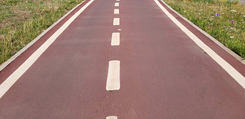 A red synthetic treadmill or bike path with white markings