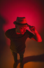 A man wearing a hat is standing in front of a red background