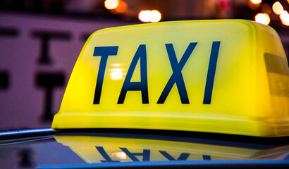 Yellow and black sign of a taxi put on a car at night
