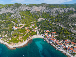 AERIAL: Scenic shot of a small beachfront settlement on a Croatian island Hvar - obrazy, fototapety, plakaty