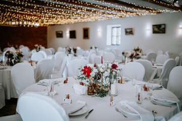 Valmiera, Latvia - August 19, 2023 - Elegantly set wedding reception tables with white chairs, tablecloths, and vibrant floral centerpieces under twinkling lights...