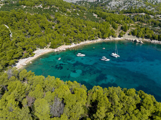 AERIAL: Breathtaking shot of a green secluded bay on a sunny day in the Adriatic