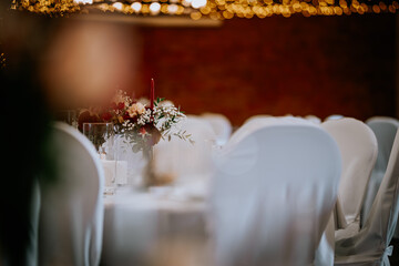 Valmiera, Latvia - August 19, 2023 - An elegantly set wedding reception table, focused on a floral...