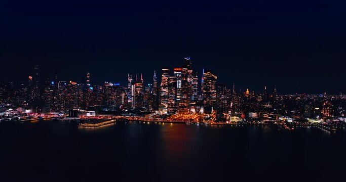 Dazzling skyline of modern New York at night. Approaching the waterfront of metropolis over the East River.