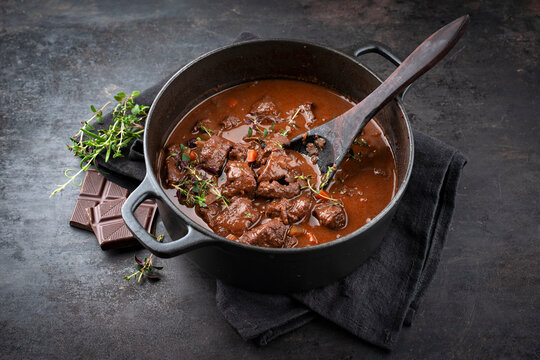 Traditionelles deutsches geschmortes Hirschragout mit Gem&uuml;se und Kr&auml;uter in s&uuml;&szlig; w&uuml;rziger Schokoladen Rotweinso&szlig;e serviert als Nahaufnahme in einer Nordic Design Schmortopf mit Textfreiraum