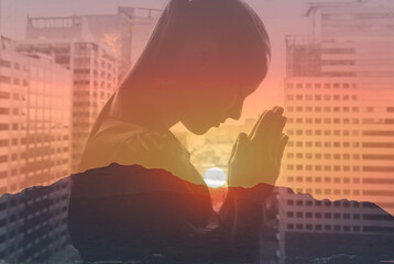 Silhouette of christian woman in the city praying at sunrise, spirituality and religion, female praying to god. Christianity concept.