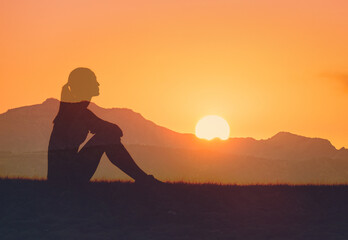 Young woman sitting watching the sunrise feeling at peace in nature 