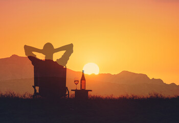 Young woman sitting back facing the sunrise feeling happy  at peace in nature 