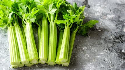 A close-up of crisp celery stalks, arranged neatly on a light grey background to accentuate their fresh, bright green hue and natural texture, with space for text