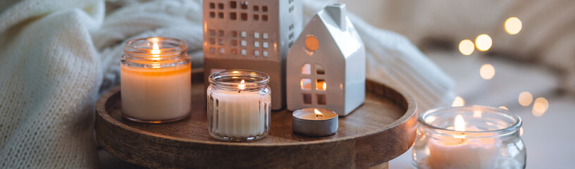 Winter home aromatherapy, cozy atmosphere. Burning aroma candles on wooden tray, knitted blanket. Christmas scent, elegant interior design. Relaxation, detention, meditation, cosiness banner