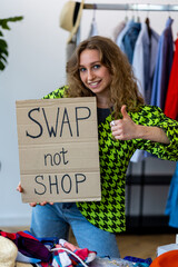 Young generation z girl holding banner with words swap not shop promoting sustainable fashion,...