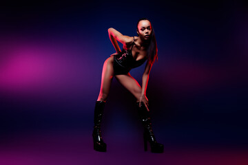 Photo of african american girl in black leather bodysuit posing isolated dark multicolor neon background