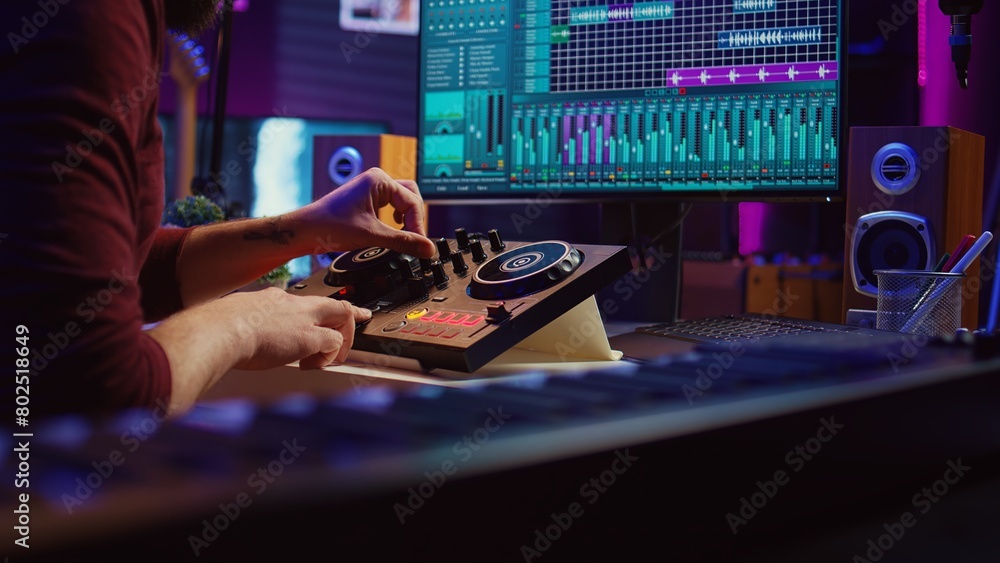 Poster Experienced audio engineer uses mixing board to create new song in recording home studio. Post production equipment and tools on computer, operates digital audio workstation software. Camera B.