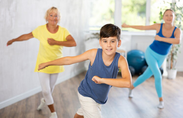 Fototapeta premium Family of three is actively moving while performing dance fitness exercises.