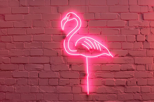 A pink flamingo-shaped neon sign glowing against a pink brick wall.