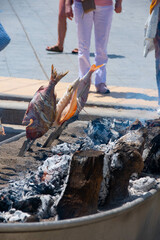 Skewers of octopus, sea bream, shrimp and sardines, grilled over a wood fire in a boat on the sand of the beach. Typical dish from Malaga, Andalusia, Spain.