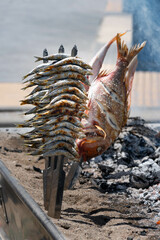 Skewers of octopus, sea bream, shrimp and sardines, grilled over a wood fire in a boat on the sand of the beach. Typical dish from Malaga, Andalusia, Spain.