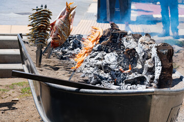 Skewers of octopus, sea bream, shrimp and sardines, grilled over a wood fire in a boat on the sand of the beach. Typical dish from Malaga, Andalusia, Spain.