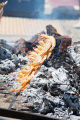 Skewers of octopus, sea bream, shrimp and sardines, grilled over a wood fire in a boat on the sand of the beach. Typical dish from Malaga, Andalusia, Spain.