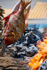 Skewers of octopus, sea bream, shrimp and sardines, grilled over a wood fire in a boat on the sand of the beach. Typical dish from Malaga, Andalusia, Spain.
