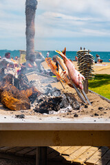 Skewers of octopus, sea bream, shrimp and sardines, grilled over a wood fire in a boat on the sand of the beach. Typical dish from Malaga, Andalusia, Spain.