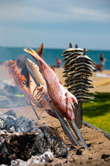 Skewers of octopus, sea bream, shrimp and sardines, grilled over a wood fire in a boat on the sand...