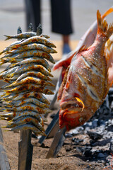 Skewers of octopus, sea bream, shrimp and sardines, grilled over a wood fire in a boat on the sand of the beach. Typical dish from Malaga, Andalusia, Spain.