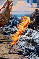 Skewers of octopus, sea bream, shrimp and sardines, grilled over a wood fire in a boat on the sand of the beach. Typical dish from Malaga, Andalusia, Spain.