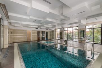 Luxury indoor private pool with waterfall jet, Jacuzzi and ladder. Panoramic windows.
