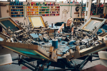 Printing shop worker adjusting screen carousel printing machine for work