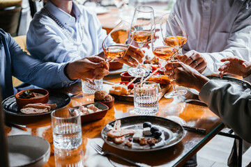 Friends having a dinner party with different kinds of appetizers and rose wine.