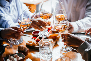 Friends having a dinner party with different kinds of appetizers and rose wine.