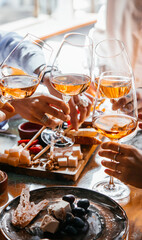 Friends having a dinner party with different kinds of appetizers and rose wine.
